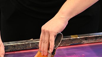 Foto einer Person die Stoffe mit einem Pinsel färbt