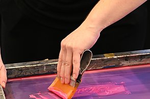 Foto einer Person die Stoffe mit einem Pinsel färbt