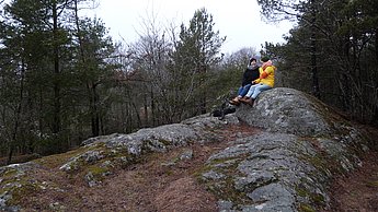 Zwei Personen sitzen auf einem Stein im Wald