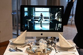 Foto eines Tisches auf dem Teller, Besteck, Tücher und ein Monitor oben drauf stehen 