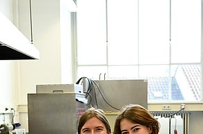 Zwei Personen posieren für das Foto. Eine Person hält eine Schüssel mit grünem Inhalt