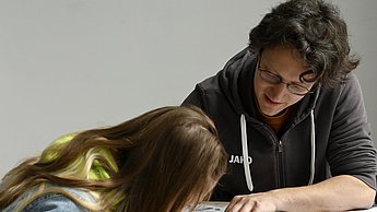 Studentin beobachtet jemanden beim zeichnen