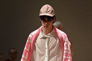 Foto eines Models, welches weiß angezogen ist und einen rosanen Schal trägt