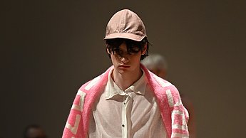 Foto eines Models, welches weiß angezogen ist und einen rosanen Schal trägt