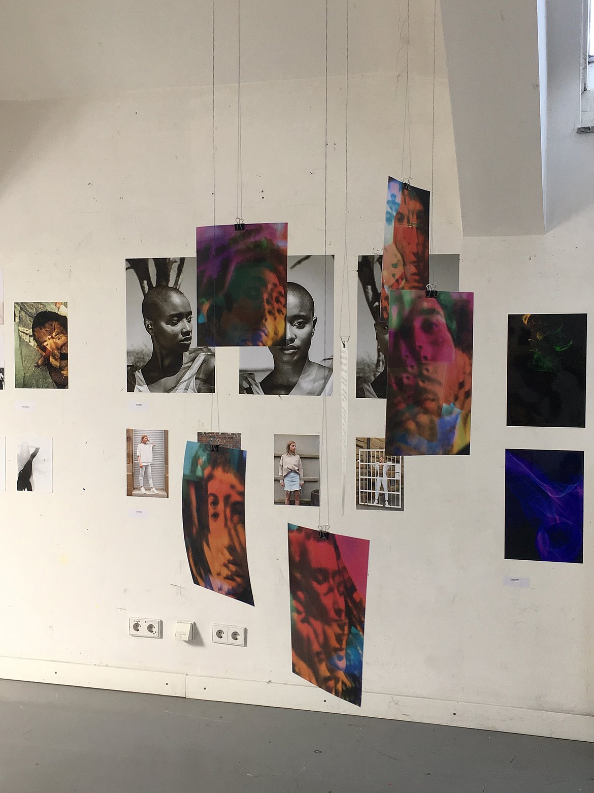 Fotografie-Ausstellung: Verschiedene Bilder hängen an der Wand und von der Decke