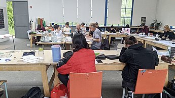 Studenten sitzen an verschiedenen Tischen