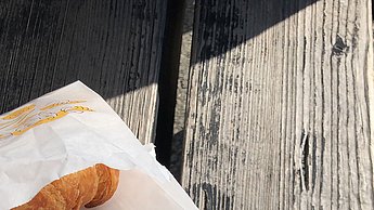 Foto eines Brötchens in einer Tüte und Cafe in einem Becher