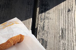 Foto eines Brötchens in einer Tüte und Cafe in einem Becher
