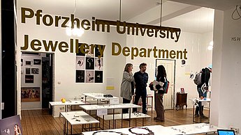 Personen im Gebäude mit Aufschrift "Pforzheim University Jewellery Department"
