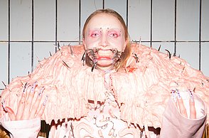 Eine Frau in einem rosa Kostüm zeigt ihre Fingernägel zur Kamera 