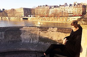 Person sitzt auf einer Brücke