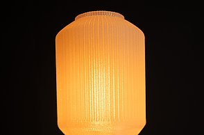 Dargestellt wird der 3D-gedruckte, zylinderförmige Lampenschirm mit einer vertikalen Linienstruktur. 