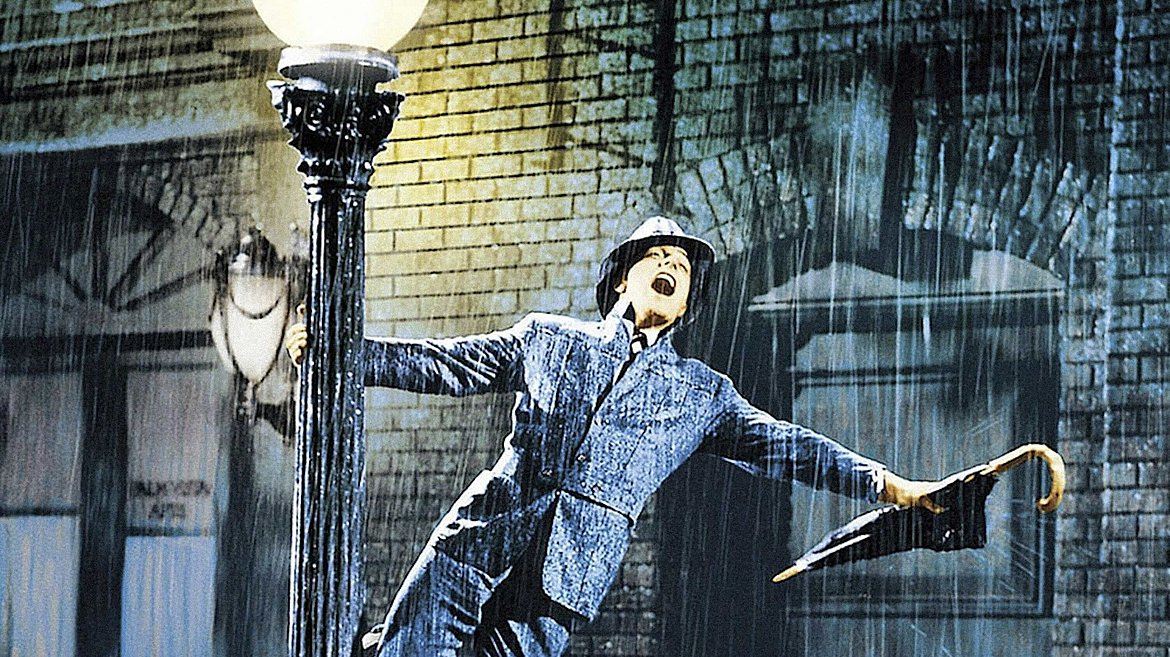 Mann steht im Regen während er einen geschlossenen Regenschirm hält.