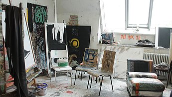 Foto eines Ateliers mit verschiedenen Gemälden im Zimmer