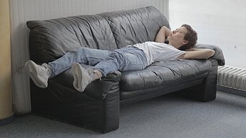 Ein Mann liegt entspannt auf einem Sofa