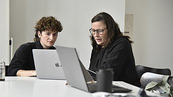 Zwei Personen arbeiten an ihren Laptops