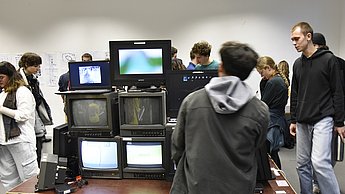 Personen laufen um gestapelte Fernseher 