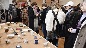 Menschen betrachten Tassen auf einem Tisch
