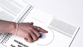 Eine Hand zeigt auf ein Abbild im Buch