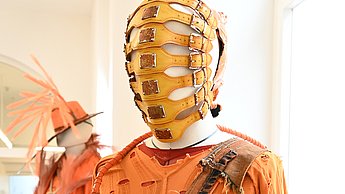 Foto eines orangenen Kostüms mit einer gelben Maske