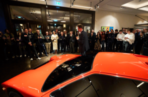 Im Hintergrund stehen Menschen, welche ein ausgestelltes Auto betrachten