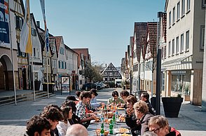 Menschen sitzen an einem langen Tisch