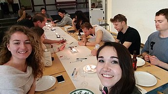 Personen sitzen an einem Tisch und essen zusammen