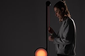 Dargestellt wird eine weibliche Person, die die Funktion und den Mechanismus der Leuchte verdeutlicht