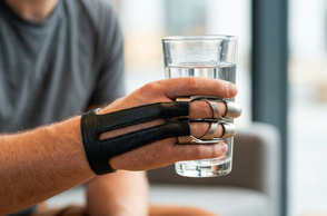 Abgebildet ist eine Hand mit einer entworfenen Prothese, welche ein Glas greift.