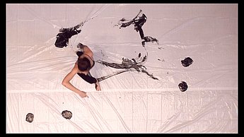 Eine Person verbreitet schwarze Farbe auf einer großen Leinwand