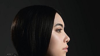 Foto einer Person mit einem Schmuckstück, dass von ihren Haaren auf ihre Schulter fällt