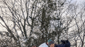 Foto einer Gruppe die mit einem Schneemann vor einem Baum posiert