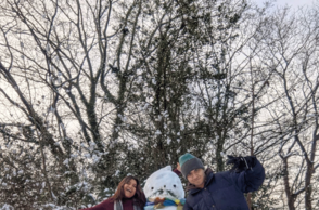 Foto einer Gruppe die mit einem Schneemann vor einem Baum posiert