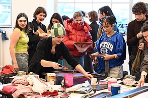 Foto von einer Gruppe von Personen die vor einem Tisch mit bedrucktem Material stehen