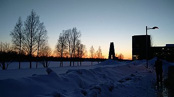 Foto vom verschneiten Campus bei einem Sonnenuntergang