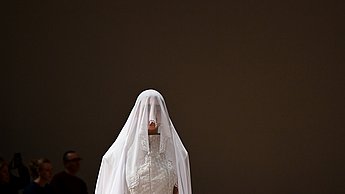 Foto eines Models, welches ein weißes, langes Tuch auf dem Kopf trägt