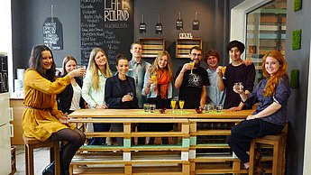 Gruppe Menschen sitzt um einen Holztisch