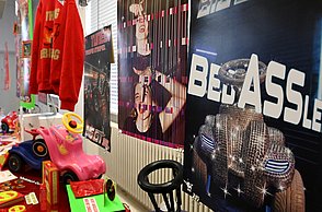 Foto einer bunten Ausstellung mit Plakaten, Kleidung und Bobbycars 