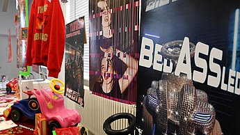 Foto einer bunten Ausstellung mit Plakaten, Kleidung und Bobbycars 