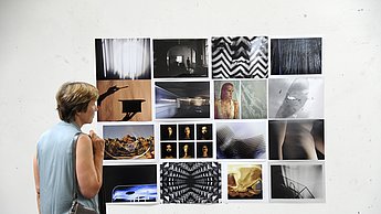 Eine Frau bestaunt eine Collage von aufgehängten Bildern