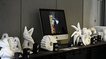Verschiedene Skulpturen stehen auf einem Tisch neben einem Computerbildschirm