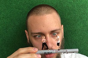 Bild eines Mannes, der zwei winzige Menschen auf einem Fineliner balancieren sieht