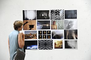 Eine Frau bestaunt eine Collage von aufgehängten Bildern