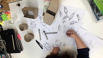 Person zeichnet Ideen auf Papier