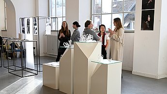 Personen stehen hinter einer Skulptur aus Formen