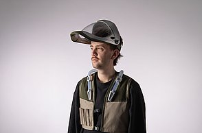 Dargestellt wird eine männliche Person mit nach oben geklapptem Schweiß-Helm