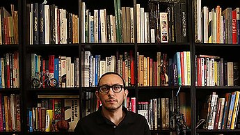 Mann steht vor Bücherschrank