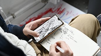 Person skizziert von Bild von ihrem Handy in ihr Skizzenbuch 