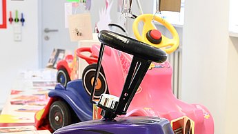 Foto eines modifizierten Bobbycars, welches lila mit schwarzen Stickern ist