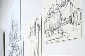 Foto einer Wand an welcher verschiedene Skizzen hängen